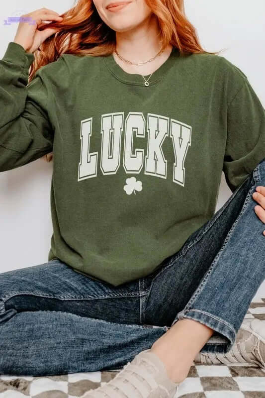 Woman in green long sleeve "LUCKY" shirt with shamrock, styled casually for St. Patrick's Day celebration.