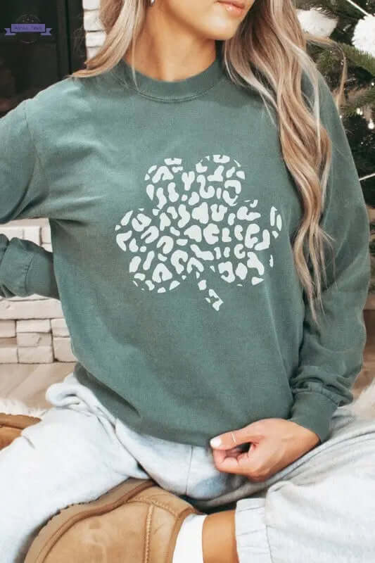 Woman wearing a leopard shamrock graphic long sleeve shirt for St. Patrick's Day celebration.