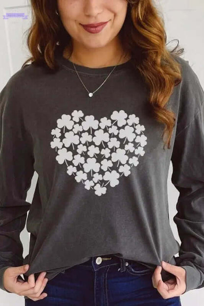 Woman wearing a gray long sleeve shirt with a clover heart graphic for St Patrick's Day celebration.