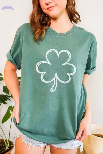 Woman wearing a green long sleeve shirt with a white shamrock design, perfect for St. Patrick's Day celebrations.